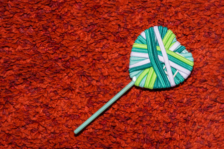 heart made of turquoise green and white rubber bands on a red carpet with a long pile in macro