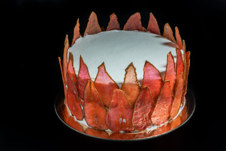white cake with slices of carmel pear on a black background