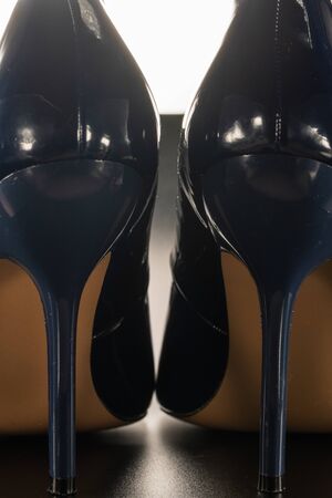 close-up of female high-heeled shoes of blue and glossy on a black backgroundの写真素材