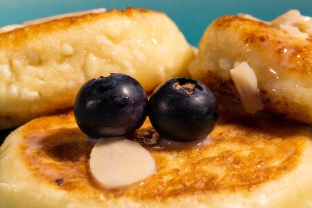 cheese pancake with almonds and blueberries poured with condensed milk on a blue plate, closeupの写真素材