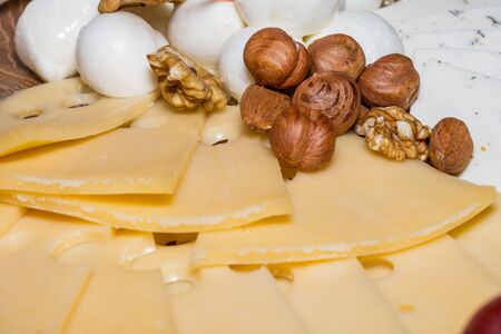 wooden tray with cheese fruit and nuts, pomegranate and grape, closeupの写真素材