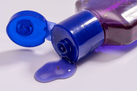 A small bottle of purple hand antiseptics with particles and a dispenser, close-up