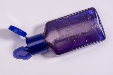 A small bottle of purple hand antiseptics with particles and a dispenser, close-upの写真素材