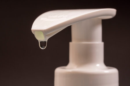 White dispenser for antibacterial soap from which soap is dripping, macro photoの写真素材