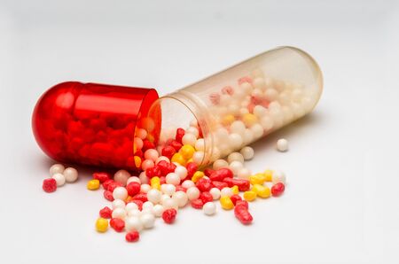 red-white tablet capsule with red-white balls on white background macroの写真素材