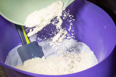 Adding almond flour to the lilac meringue, close-up.
