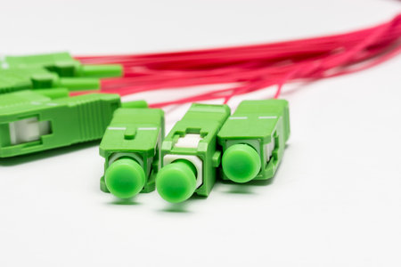 short sections of red optical cable with green connectors on a white background, close-up.の写真素材