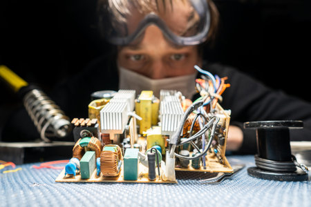 A man in glasses and a mask, with a soldering iron, repairs equipment, close-up.