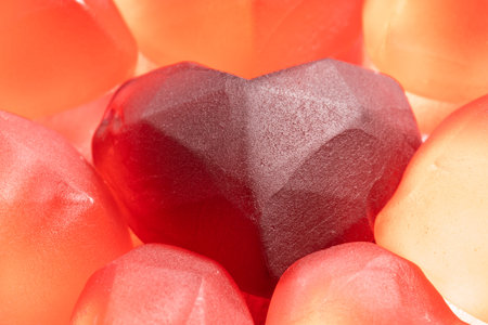 Sweet red gummies in the shape of a heart, on a light background, close-up.