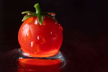 small red cherry tomatoes, in water with falling drops, frozen motion, close-upの写真素材