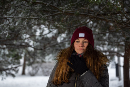 Girl in the winter, against the background of snow-covered trees, in the park.