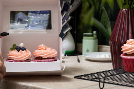 The confectioner decorates with a delicately pink cream of cupcakes in pink molds. Close-up.の写真素材