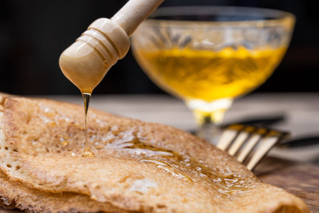 Pancakes with honey and tea on a wooden tray. gold knife and fork. Close-up.