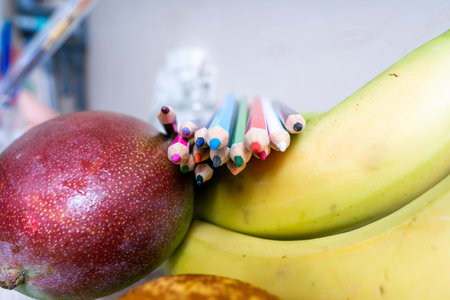Colored pencils lie on mango and banana fruit