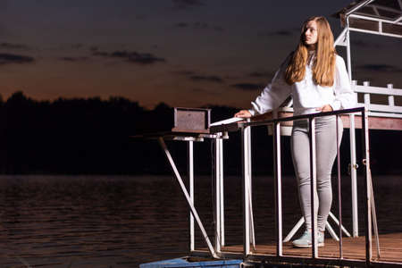 A girl on the bank of the river in a yellow swimsuit and shertas, reads. Breakfast by the river. Fruits.の写真素材