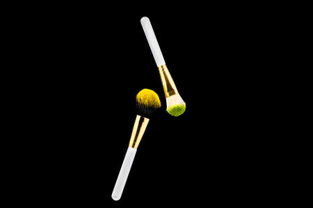Two white with gold makeup brushes on a black background. Powder brush.の写真素材