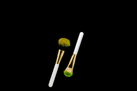Two white with gold makeup brushes on a black background. Powder brush.の写真素材