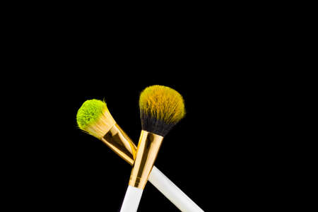 Two white with gold makeup brushes on a black background. Powder brush.の写真素材