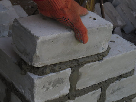 Mason builds a wall of white brick.
