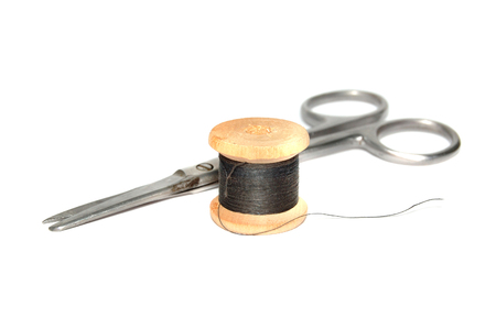 Scissors and a skein of black thread on white backgroundの写真素材