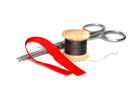 Scissors and a skein of black thread on white backgroundの写真素材