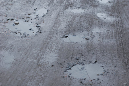Different sized holes in the road filled with water.
