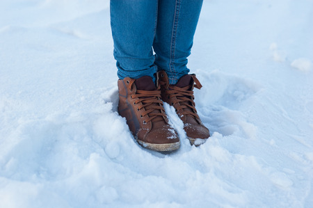 Legs of a girl with brown shoes in the snow.の写真素材