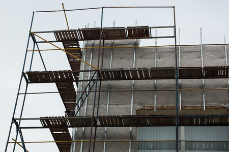 Old metal scaffolding near a tall building.の写真素材
