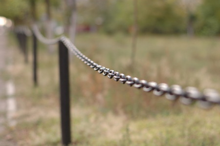 Black metal fence in the garden in the form of a chain.の写真素材