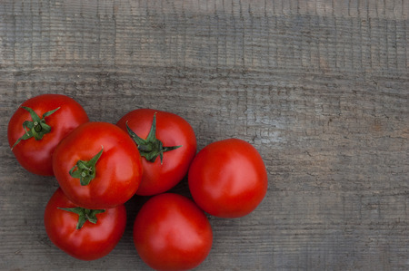 Several juicy red tomatoes on a wooden background.の写真素材