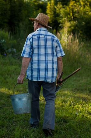 An elderly peasant man with an agricultural tool in nature.の写真素材
