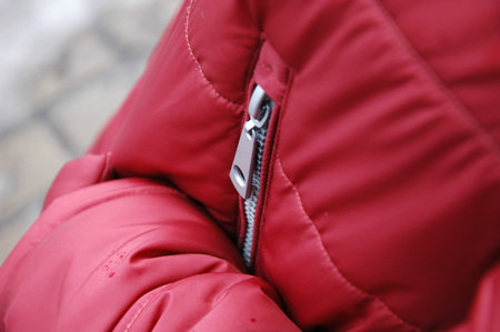 Some areas of a red jacket with rain drops on the street.