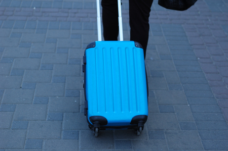 A blue traveling suitcase is taken along the path.の写真素材