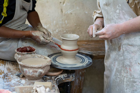 A potter teaches a child how to make a pot of clay.