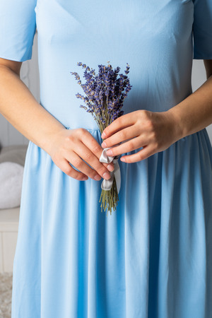 A girl in a blue dress holds a bouquet of lavender in her hands.の写真素材