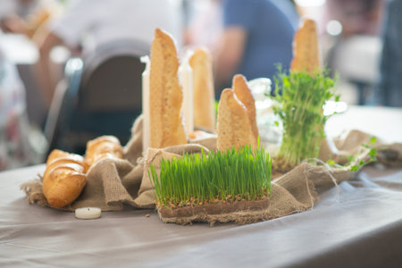Rustic bread and wheatgrass on a table setting with candlesの写真素材