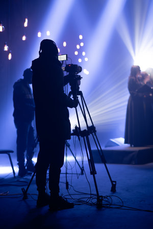 Cinematographer filming a stage performance in a studio with dramatic lightingの写真素材