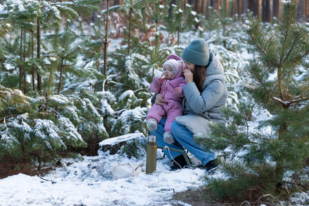 Mother with children eating in a snowy forest.の写真素材
