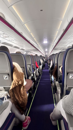 Central aisle of an airplane with passengers, view from behind showing legs and backs.の写真素材