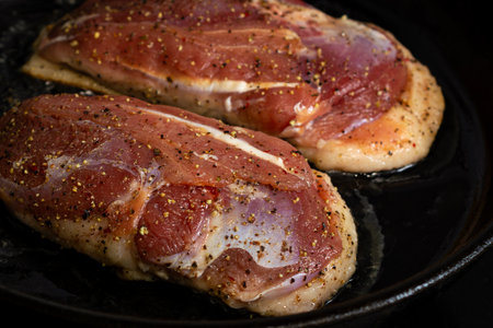 two duck breasts are fried in a pan, seasoned with salt and a mixture of peppersの写真素材