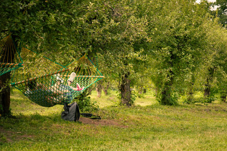 a couple (boy and girl) is lying on a hammock in a summer apple garden - the concept of summer...