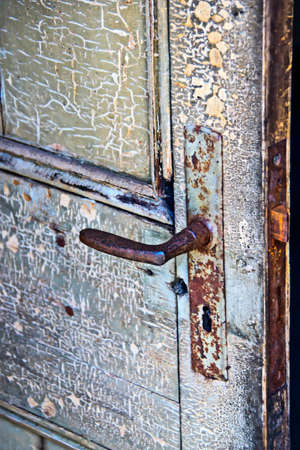 An old door with peeling paint and a rusty lock at a lost placeの写真素材