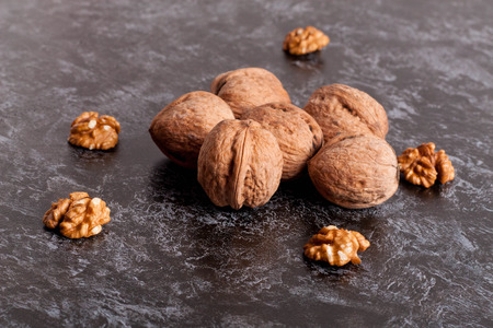 Walnut kernels and whole walnuts on black table, close up, horizontalの写真素材