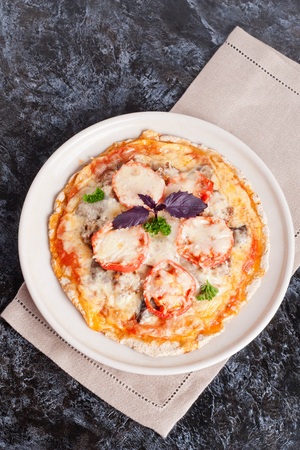 pizza with tomato sauce, cheese and greens on a plate, vertical, close-upの写真素材