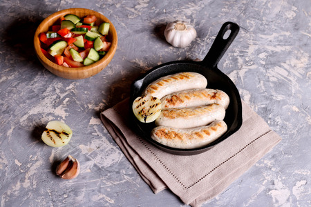 Sausages in rustic pan with onion. Top view. Frying pan with fried sausage and vegetables. Horizontalの写真素材