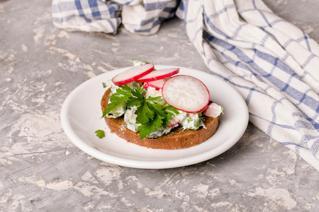 Sandwiches with cottage cheese, radish and cucumber, parsley, baking paper, white wood background, close up, horizontalの写真素材