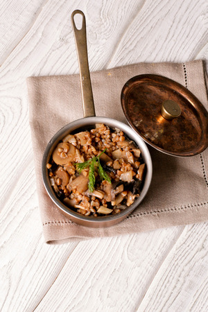 Buckwheat porridge with mushrooms in the copper pan, vertical, top viewの写真素材