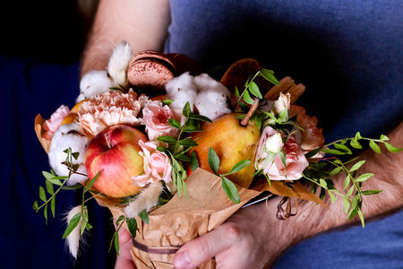 Bouquet from flowers and fruit in hands. Autumn composition. Close up, horizontalの写真素材