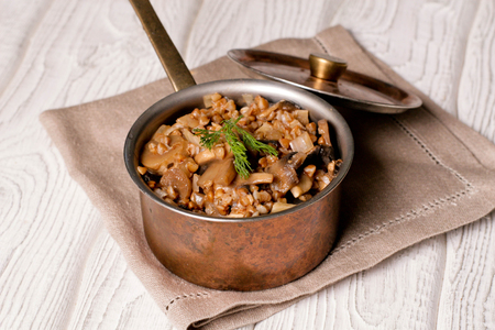 Buckwheat porridge with mushrooms in the copper pan, horizontal, close upの写真素材