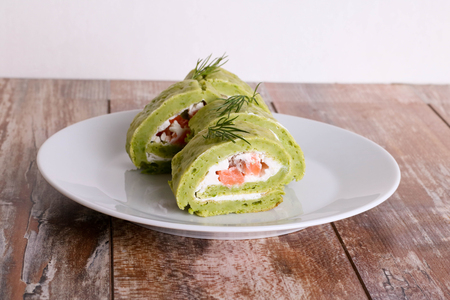 green pea roll with salmon and cottage cheese on a white plate, close up, horizontalの写真素材